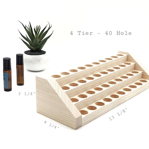 May include: A four-tiered, natural wood essential oil display rack with 40 holes. The rack is 13 1/8 inches long and 4 1/4 inches wide. Two essential oil bottles and a small succulent plant in a white pot are also in the image.