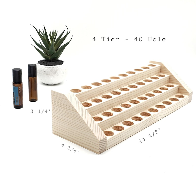 May include: A four-tiered, natural wood essential oil display rack with 40 holes. The rack is 13 1/8 inches long and 4 1/4 inches wide. Two essential oil bottles and a small succulent plant in a white pot are also in the image.