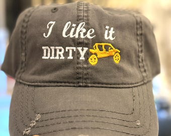 Puede incluir: Gorra de béisbol gris con la frase bordada "I like it DIRTY" y un vehículo todoterreno amarillo. La gorra tiene un aspecto desgastado con bordes deshilachados.