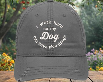 May include: A gray distressed baseball cap with white embroidery that reads "I work hard so my Dog can have nice things".