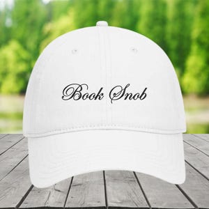May include: White baseball cap with black embroidered text that reads "Book Snob".
