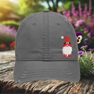 May include: A gray distressed baseball cap with an embroidered gnome wearing a red hat and white beard.