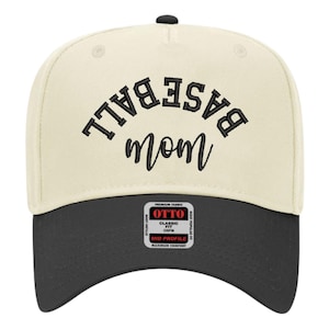 May include: A two-tone baseball cap with a cream-colored crown and a black brim. The front features black embroidered text that reads BASEBALL in an arched block font above the word mom in a cursive script. A square sticker is on the brim.