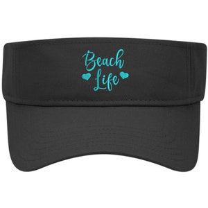 May include: Black visor with the text "Beach Life" embroidered in turquoise blue with two small hearts on either side of the word "Life".