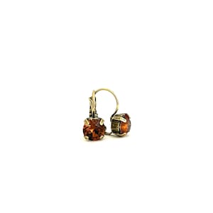 May include: A pair of lever-back earrings featuring round, amber-colored gemstones. The earrings have a vintage-style, gold-toned metal setting. The gemstones are faceted, catching the light and adding sparkle to the jewelry.