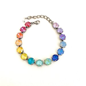 May include: A rainbow-colored crystal bracelet with a silver chain. The crystals are arranged in a gradient from red to purple.