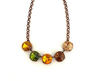 May include: A copper chain necklace with five round, faceted gemstones. The gemstones are in shades of green, yellow, and brown.