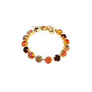 May include: A gold bracelet with a chain and a row of colorful round crystals. The crystals are in shades of orange, brown, and gray.