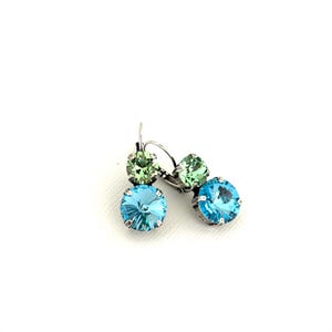 May include: A pair of earrings featuring a light blue and green crystal design. The earrings have a lever back closure and are set in a silver-tone metal. The crystals are round and faceted, reflecting light.