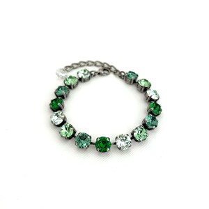 May include: A silver chain bracelet with a gradient of green crystal stones. The stones range from light green to dark green.