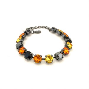 May include: A bracelet featuring a series of round, faceted gemstones in shades of black, orange, and yellow. The stones are set in a dark metal chain, creating a striking contrast. The bracelet is designed to be worn around the wrist.