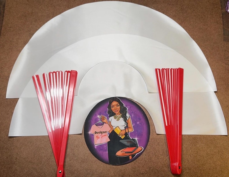 May include: Three white satin fabric fan shapes, two red and white folding fans, and a sticker with a woman wearing a shirt that says "Boss Babe" in a purple and black background.