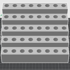 May include: A gray, stepped organizer with multiple rows of evenly spaced circular holes. The design appears to be 3D-printed, with a grid-like base and a light gray color scheme. The object is likely for storage or display.