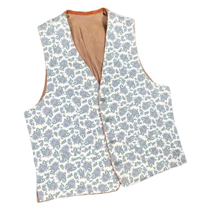 May include: A paisley patterned vest with a cream background and blue and green accents. The vest has a brown lining and trim, with four buttons down the front. The vest is a classic style.