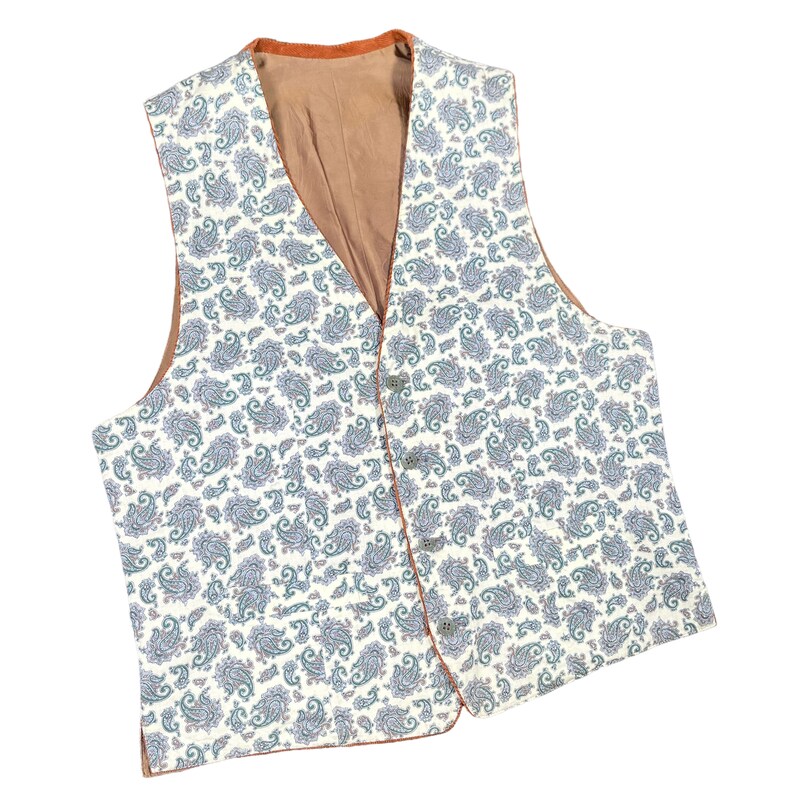 May include: A paisley patterned vest with a cream background and blue and green accents. The vest has a brown lining and trim, with four buttons down the front. The vest is a classic style.