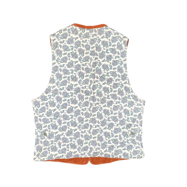 May include: A reversible vest with a paisley pattern on a cream background. The vest has a rust-colored trim and lining. The paisley pattern features blue and gray details. The vest is a classic style, suitable for layering.