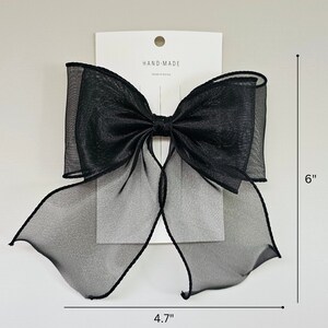 May include: A large black sheer bow with a hand-made label. The bow measures 6 inches tall and 4.7 inches wide.