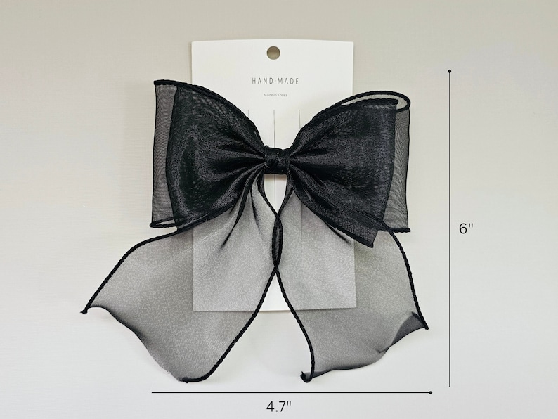 May include: A large black sheer bow with a hand-made label. The bow measures 6 inches tall and 4.7 inches wide.