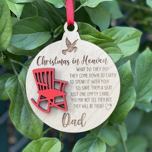May include: A wooden Christmas ornament with a red rocking chair and the text "Christmas in Heaven" and "Dad". The ornament has a white dove with an olive branch in its beak. The text reads: "What do they do? They come down to earth to spend it with you! So, save them a seat, just one empty chair, you may not see them but, they will be there!"