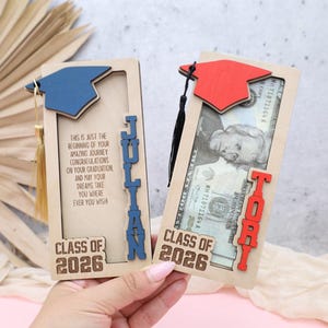 May include: Two wooden graduation gifts with mortarboard caps. One is blue with the name "Julian", the other is red with the name "Toby". Both have "Class of 2026" and a congratulatory message.