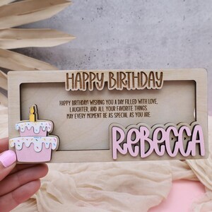 Puede incluir: Una tarjeta de cumplea&ntilde;os de madera con un pastel rosa y el texto "HAPPY BIRTHDAY! WISHING YOU A DAY FILLED WITH LOVE LAUGHTER, AND ALL YOUR FAVORITE THINGS MAY EVERY MOMENT BE AS SPECIAL AS YOU ARE REBECCA"