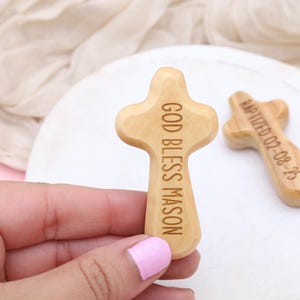 May include: Two wooden crosses with engraved text. One cross reads "God Bless Mason" and the other reads "Baptized 02-08-25".