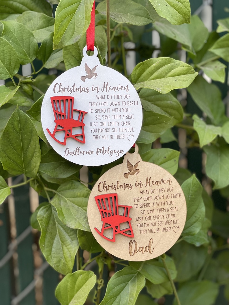 May include: Two wooden Christmas ornaments with a red rocking chair and the text "Christmas in Heaven" with a quote about loved ones coming down to earth to spend time with you. The first ornament says "Guillermo Melgoza" and the second ornament says "Dad".