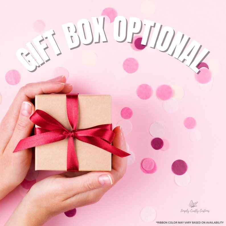 May include: A brown gift box with a red ribbon tied in a bow. The box is being held by two hands against a pink background with confetti.