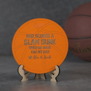 May include: Orange wooden basketball-shaped sign with the text "God scored a slam dunk when he made you my dad" and a heart with the text "Alex & Jacob".