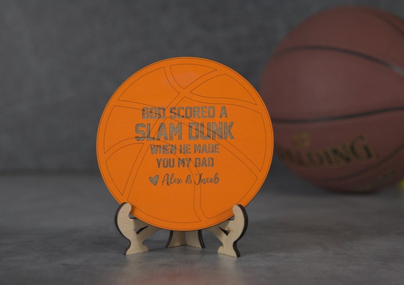 May include: Orange wooden basketball-shaped sign with the text "God scored a slam dunk when he made you my dad" and a heart with the text "Alex & Jacob".