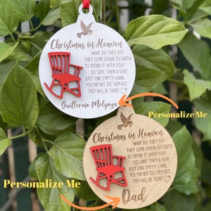 May include: Two wooden Christmas ornaments with a red rocking chair design. The ornaments have the text "Christmas in Heaven" and a poem about saving a seat for loved ones who have passed away. One ornament has the name "Guillermo Melgoza" and the other has the word "Dad". Both ornaments have the text "Personalize Me".