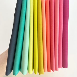 May include: A rainbow of fabric swatches in various shades of blue, green, yellow, orange, pink, and red.