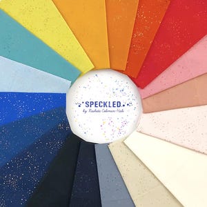 May include: A color wheel of speckled fabric swatches in various shades, including blue, yellow, orange, and pink. The swatches are arranged around a white circle with the text "SPECKLED" and the maker's name. The fabrics have a speckled pattern.