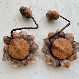 May include: Two brown felt and pine cone flower ornaments with brown wire stems.
