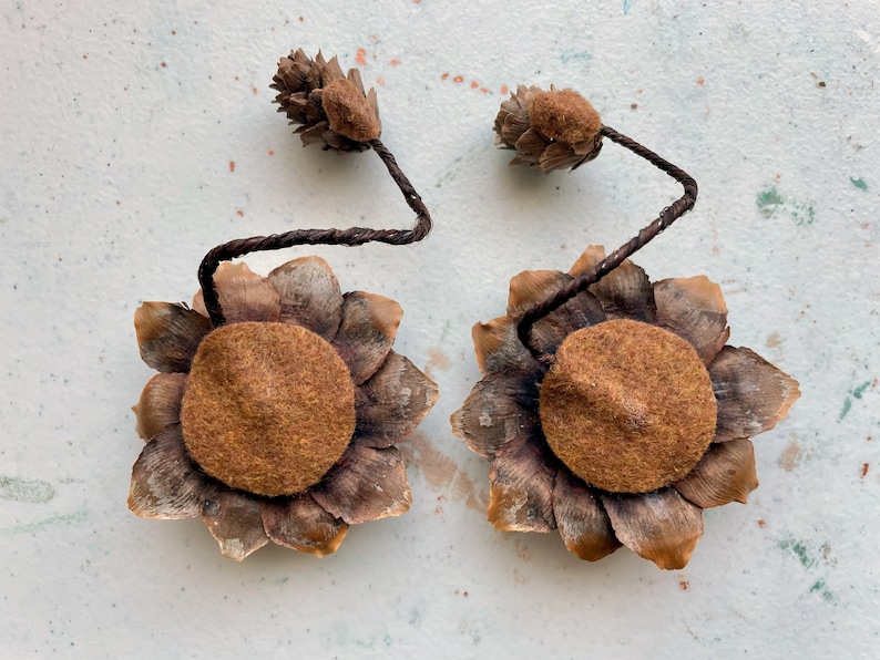May include: Two brown felt and pine cone flower ornaments with brown wire stems.