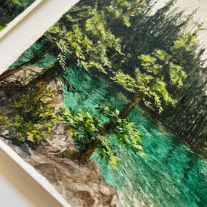Peut inclure: Peinture &agrave; l'aquarelle d'un paysage pittoresque avec un lac turquoise et des arbres verdoyants. L'&oelig;uvre capture la beaut&eacute; naturelle d'une for&ecirc;t avec des coups de pinceau d&eacute;taill&eacute;s et une atmosph&egrave;re sereine. La peinture est sur papier textur&eacute;.