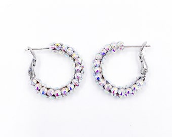 May include: A pair of silver hoop earrings with iridescent crystal accents.