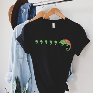 May include: Black t-shirt with a green chameleon and five green quotation marks printed on the front.