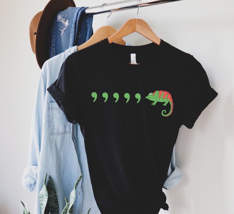May include: Black t-shirt with a green chameleon and five green quotation marks printed on the front.