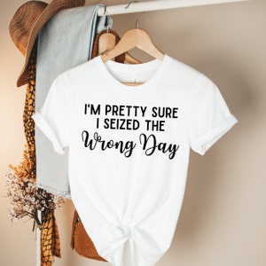 May include: White t-shirt with black text that reads "I'm pretty sure I seized the wrong day."