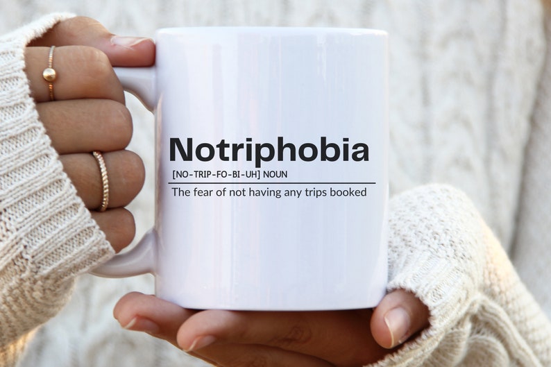 May include: White ceramic mug with black text that reads "Notriphobia [NO-TRIP-FO-BI-UH] NOUN The fear of not having any trips booked"