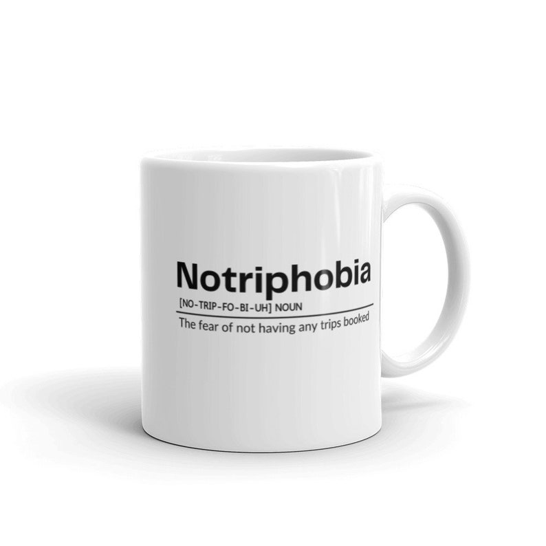 May include: White ceramic mug with black text that reads "Notriphobia [NO-TRIP-FO-BI-UH] NOUN The fear of not having any trips booked"