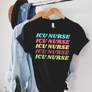K&ouml;nnte beinhalten: Schwarzes T-Shirt mit dem Text "ICU NURSE", der f&uuml;nfmal in Regenbogenfarben wiederholt wird.