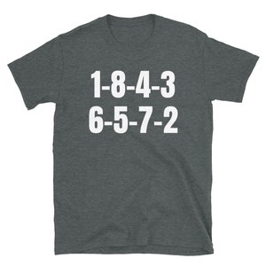 Peut inclure: Un t-shirt gris fonc&eacute; avec du texte blanc qui dit "1-8-4-3 6-5-7-2".
