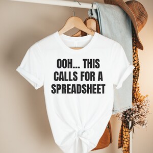 Può includere: Maglietta bianca con testo nero che dice "Ooh... This Calls For A Spreadsheet".