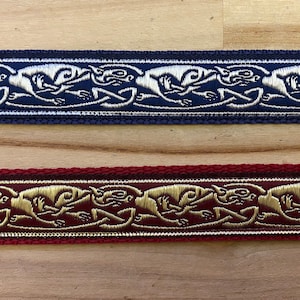 May include: Two woven fabric trims featuring a repeating pattern of stylised animal figures. The top trim is navy blue with silver thread, the bottom trim is burgundy with gold thread.