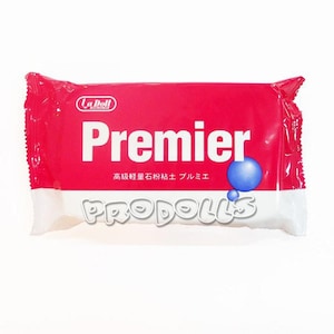 Könnte beinhalten: Eine rot-weiß verpackte La Doll Premier Lufttrocken-Tonpackung. Das Wort "Premier" steht in großen weißen Buchstaben. Eine blaue Kugelgrafik befindet sich auf der rechten Seite. Der Markenname "PRODOLLS" steht unten. Japanischer Text ist ebenfalls sichtbar.