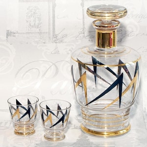 May include: A set of three vintage glass decanters with a geometric design in black and gold. The decanters are made of clear glass and have a gold rim.