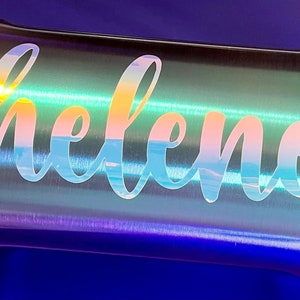 May include: A stainless steel tumbler with a iridescent finish and the name "helene" engraved on the side.