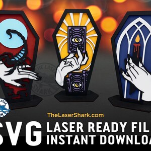 May include: Three black coffin-shaped wooden stands with different designs. The first stand has a blue background with a white hand holding a scorpion. The second stand has a yellow background with a white hand holding a tarot card with an eye design. The third stand has a blue background with a white hand holding a candle.